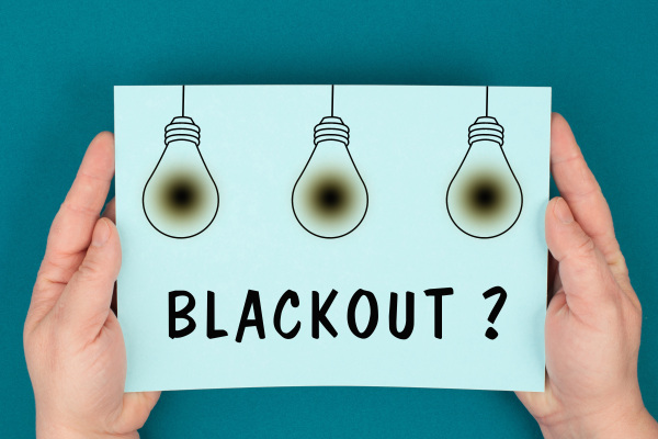 Hände halten ein Schild auf dem Blackout steht.